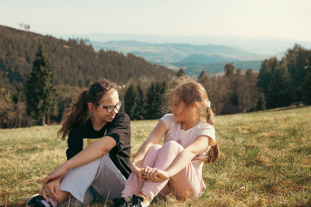 Two girls in nature in the mountains laugh merrily and have a great time together. Friendship and fun - Photo, Image