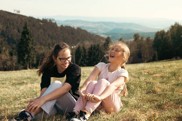 Zwei Mädchen in der Natur in den Bergen lachen fröhlich und haben eine tolle Zeit miteinander. Freundschaft und Spaß - Foto, Bild