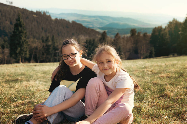 Dwie dziewczyny w przyrodzie w górach śmieją się wesoło i świetnie się bawią. Przyjaźń i zabawa - Zdjęcie, obraz