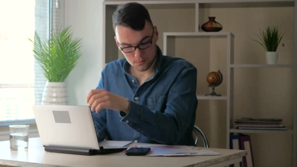 Egy fiatal, jóképű, szemüveges fiatalember nézi át a számítógép tartalmát, fáradt és elalszik. Meleg otthoni környezet. Lassú mozgás.... - Felvétel, videó