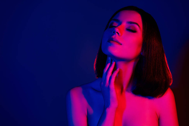 Fénykép a lány érintse meg a nyak ujját úgy érzi, érzékenység közeli szemek elszigetelt neon futurisztikus színes háttér. - Fotó, kép