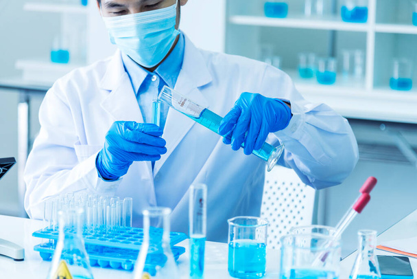 Scientist man holding sample blood test tube in science laboratory. Doctor clinic healthcare technician lab testing blood sample diagnosis. Asian man scientist working in hiv testing medical lab. - Φωτογραφία, εικόνα