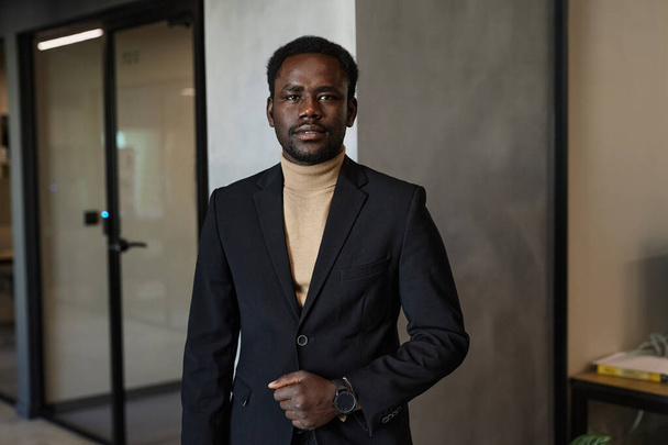 Талия портрет молодого стильного чернокожего человека в офисном здании, смотрящего в камеру - Фото, изображение