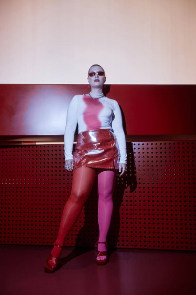Fashion portret van jonge vrouw dragen rode mini rok poseren met vertrouwen in futuristische set - Foto, afbeelding