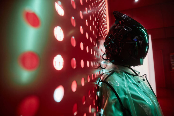 Futuristische Seitenansicht Porträt einer Person mit schwarzer Robotermaske gegen Rot, Kopierraum - Foto, Bild