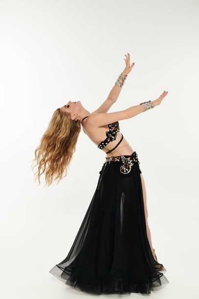 A captivating young woman in a black dress gracefully dancing and swaying. - Photo, Image