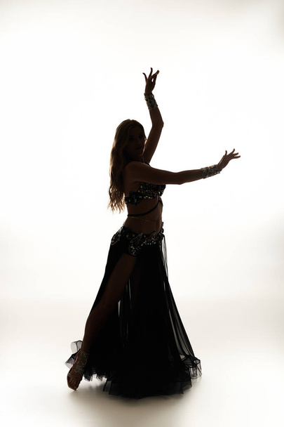 A captivating young woman in a black dress swirls gracefully while performing a belly dance. - Foto, imagen
