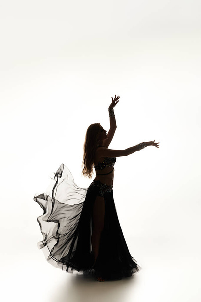 Fiatal nő eleganciával táncol fekete ruhában. - Fotó, kép