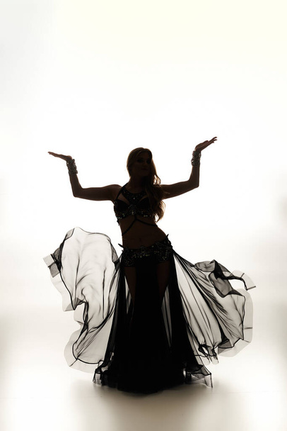 Lumoava nuori nainen mustassa mekossa tanssii sulavasti.. - Valokuva, kuva