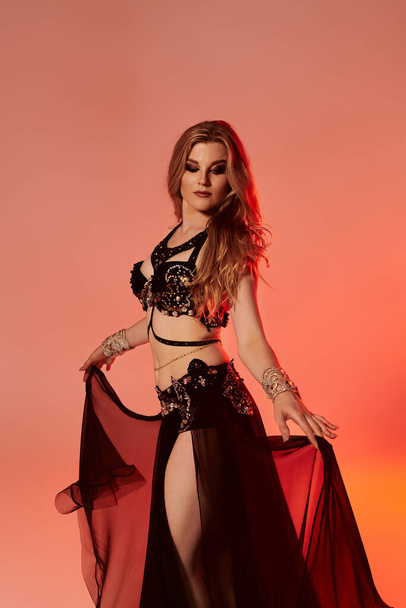 Young woman in captivating black and red attire, gracefully dancing a mesmerizing belly dance. - Foto, afbeelding