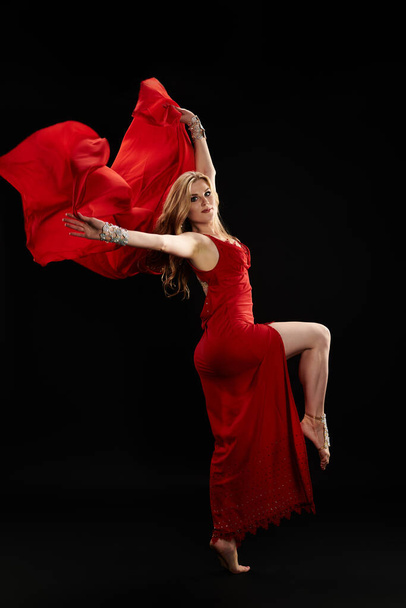 Красива жінка в червоній сукні витончено танцює. - Фото, зображення