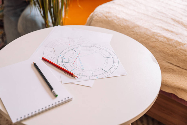 Natal chart on white paper with pencils on a round table. - Foto, Bild