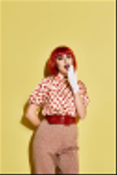 A vibrant redhead woman adorned in polka dots and bold makeup against a yellow backdrop, resembling a character from comics. - Photo, Image