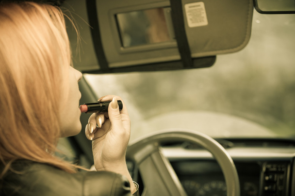 Girl painting her lips in the car. - Zdjęcie, obraz