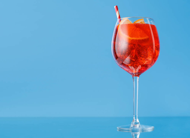 Aperol Spritz Cocktail mit Orangenscheibe und Eis auf Blau mit Kopierfläche - Foto, Bild