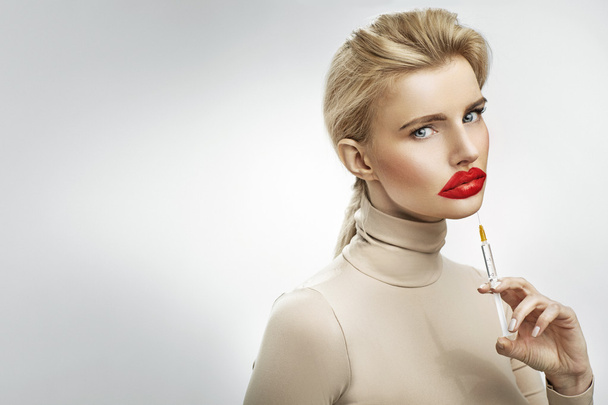 Overdreven injectie aan de lippen van een mooie blonde - Foto, afbeelding