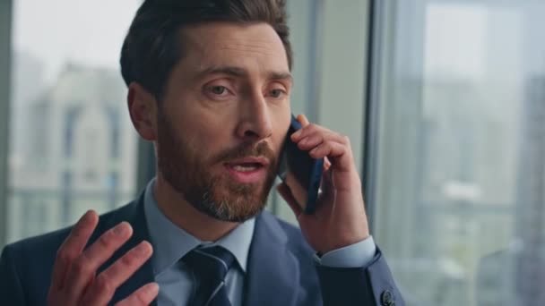 Confident businessman speaking cellphone standing at panoramic window luxury office closeup. Business manager talking phone solving work tasks remotely. Handsome entrepreneur having smartphone call - Footage, Video
