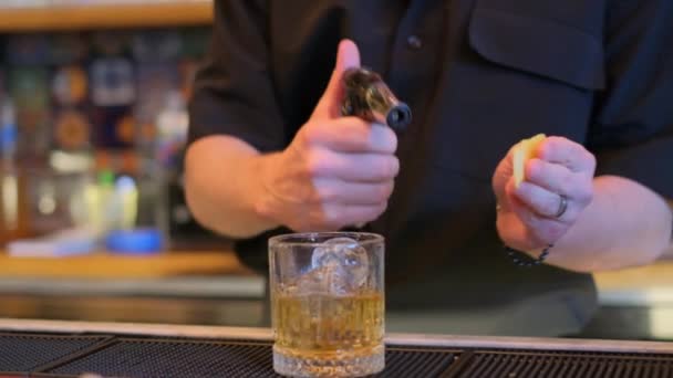 Bir barmen ustalıkla buz küpleriyle dolu bir bardağa kokteyl dolduruyor ve içki hazırlama sanatını sergiliyor. - Video, Çekim