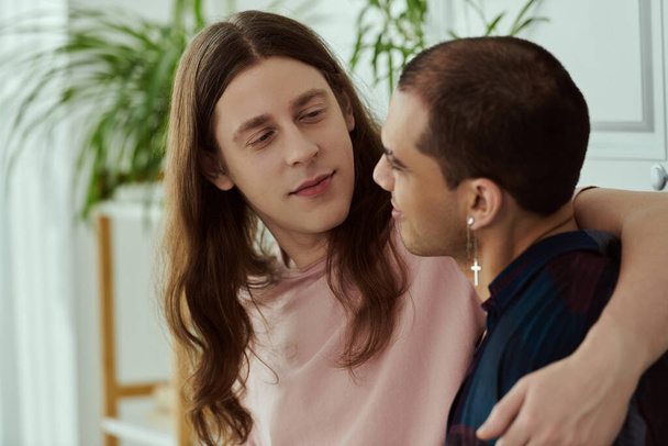 Een gay paar in casual kleding omarmen elkaar liefdevol thuis. - Foto, afbeelding