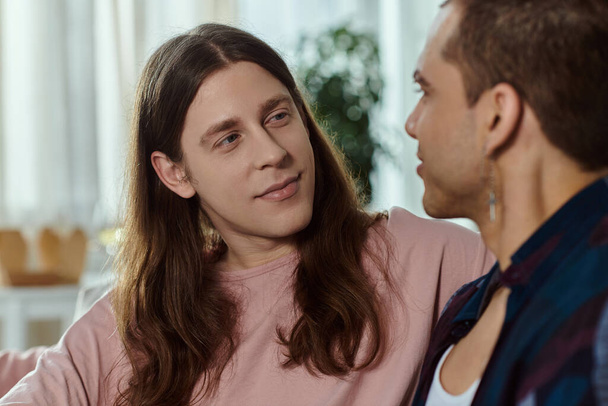 Un couple gay en vêtements décontractés se tiennent ensemble, absorbé dans la conversation. - Photo, image