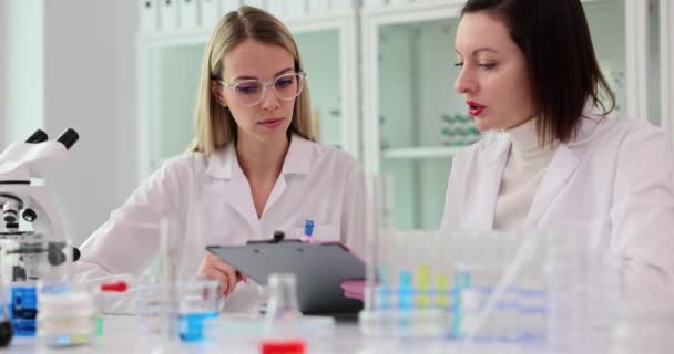 Dos científicos realizan experimentos en un laboratorio y registran datos. Trabajo científico conjunto de dos asistentes de laboratorio - Metraje, vídeo