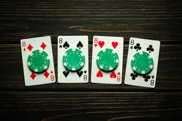 Erittäin mielenkiintoinen ja uhkapeli pokeria onnistunut voittavan yhdistelmän neljä laatuaan tai quads. Pelikortit ja vihreät sirut mustalla vintage-pöydällä klubilla. - Valokuva, kuva