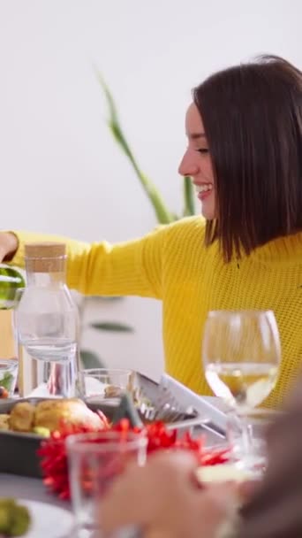 Pystysuora. Kaunis valkoinen keltainen nainen istuu pöydässä tarjoillen valkoviiniä ilolla kotona syntymäpäiväjuhlissa. Onnellinen perhe ihmiset eri sukupolvien nauttia aterian yhdessä kotielämässä - Materiaali, video