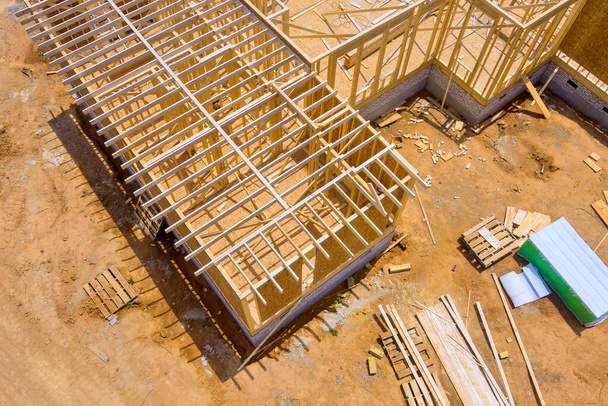 Een onder constructie woonhuis bestaat uit onafgewerkte frames houten balken tijdens de bouw - Foto, afbeelding