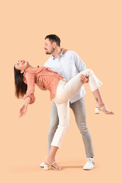 Glückliches junges Paar tanzt auf beigem Hintergrund - Foto, Bild