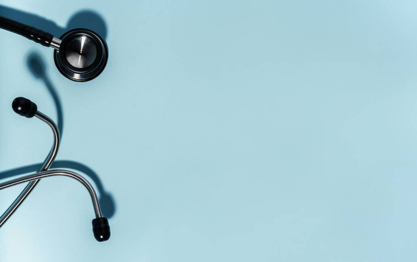 Vista superior de um estetoscópio deitado sobre um fundo azul claro, representando cuidados de saúde e exame médico. Ideal para temas de saúde e médicos - Foto, Imagem