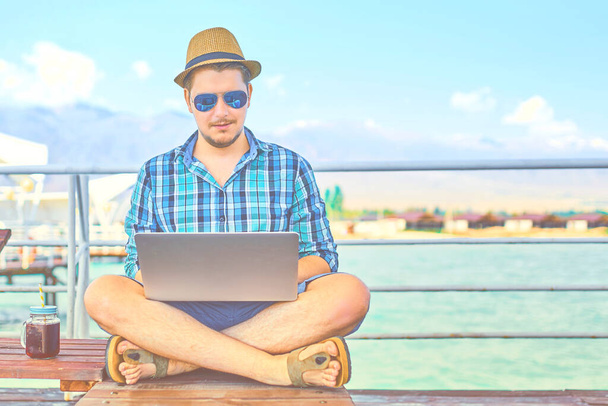 Ein Mann am Wochenende, auf See, an einem Laptop arbeitend. - Foto, Bild