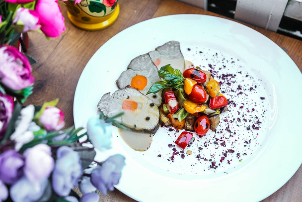 Un piatto bianco è decorato con una varietà di diversi tipi di cibo, creando un display colorato e appetitoso. - Foto, immagini