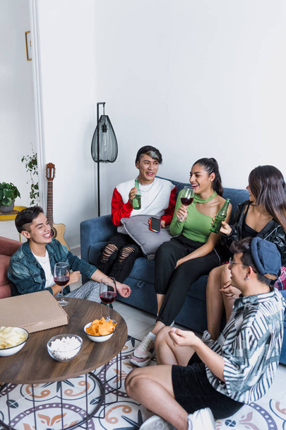 Gruppe lateinamerikanischer LGBT-Freunde, die zu Hause in Mexiko Pizza essen, Getränke trinken und Spaß haben, hispanische homosexuelle und lgbtq-Gemeinschaft in Lateinamerika in Party - Foto, Bild