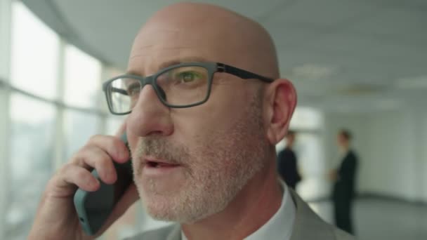 Zblízka zralý bělošský generální ředitel v brýlích volání obchodní partner na mobilním telefonu uvnitř - Záběry, video