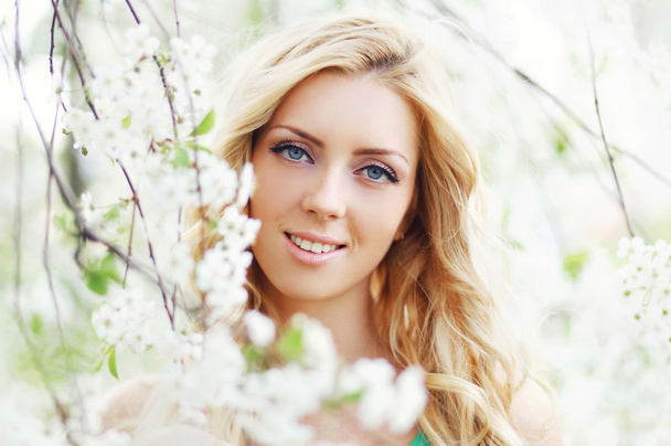 Closeup portrait of a beautiful woman enjoying smell petals in a - Photo, Image