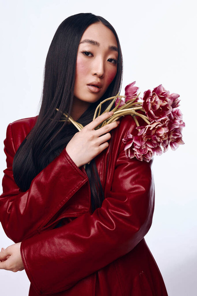 Beautiful Asian Woman in Red Leather Jacket Holding Bouquet of Pink Flowers in Spring Park - Photo, Image