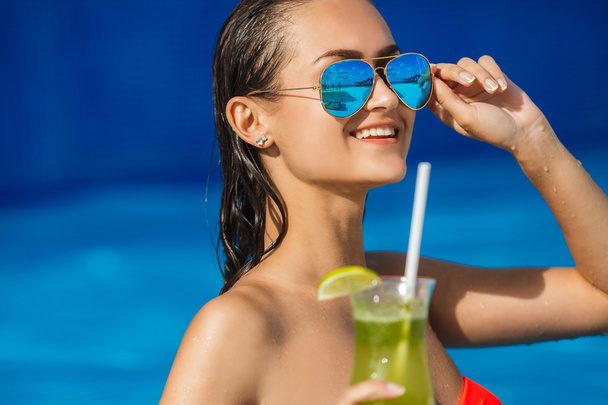 Elegant young woman in the pool with a cocktail. - Fotoğraf, Görsel