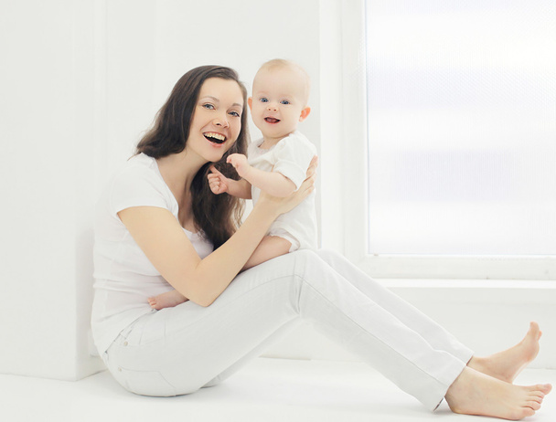 Happy young smiling mother with baby at home in white room near  - Foto, Bild