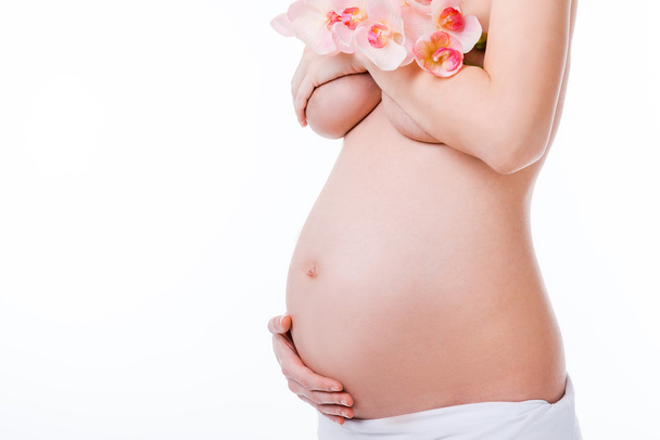 Mujer embarazada cubriendo pecho por flor
 - Foto, Imagen