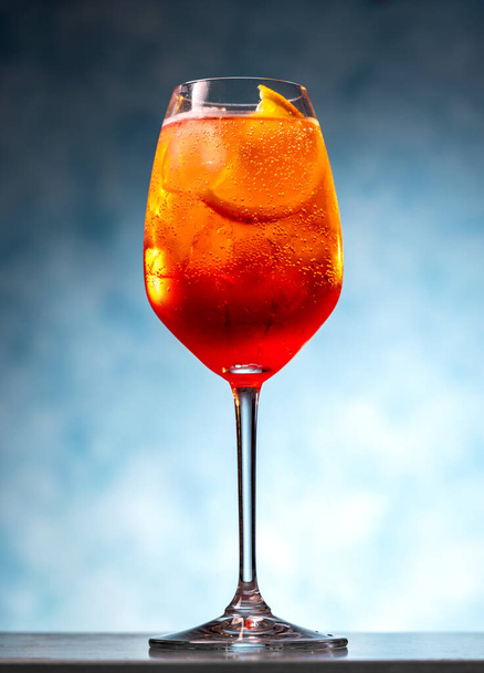 Primo piano di cocktail di spritz di aperol in bicchiere da vino su sfondo blu - Foto, immagini