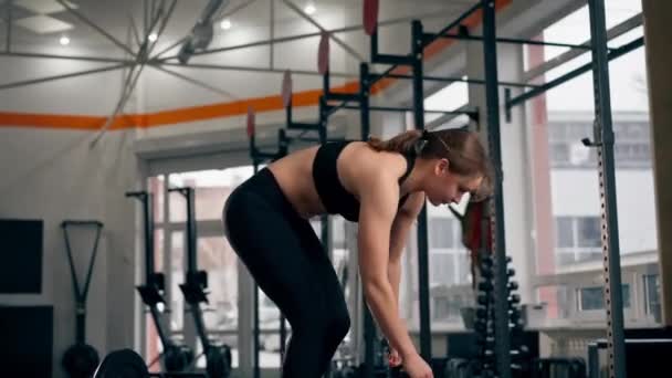 En el gimnasio una chica entrenadora se abalanza en el suelo después de trabajar con una barra saltando mientras está acostada - Metraje, vídeo