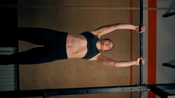 vertical video low shot in the gym a coach girl in black leggings and a top weighs on the horizontal bar - Footage, Video