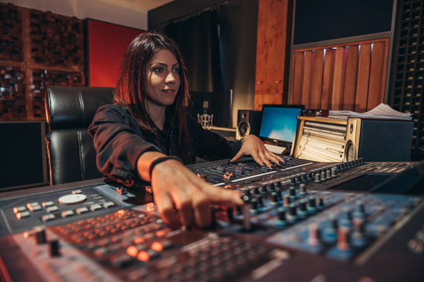 Genç bayan müzik yapımcısı stüdyosundayken bir miksaj stüdyosunda çalışıyor. - Fotoğraf, Görsel