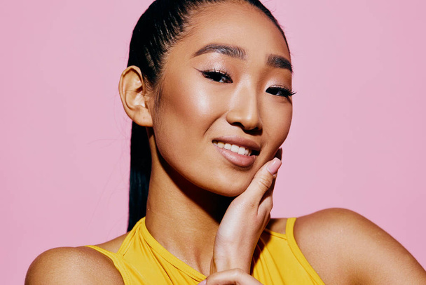 Γυναίκα χαμόγελο ροζ ομορφιά έκφραση πορτρέτο ελκυστικό νεαρό χέρι lifestyle μόδας μοντέλο στούντιο μελαχρινή διασκέδαση πρόσωπο έκπληξη μοντέρνο κίτρινο closeup - Φωτογραφία, εικόνα