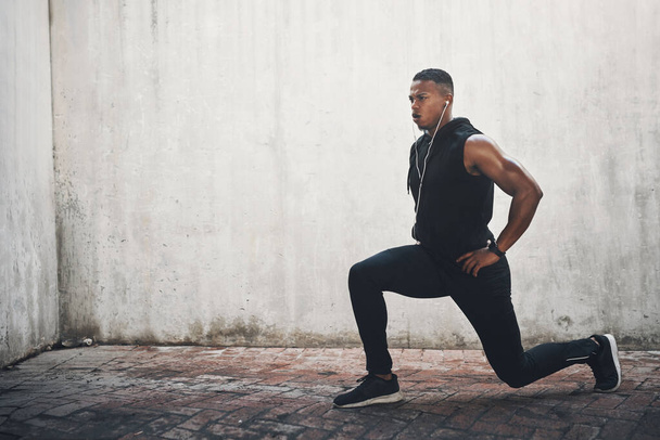 Man, exercise and lunge with earphones in city for strong muscle, balance and mockup space by wall. Male person, music and workout for legs with listening, health or audio streaming in New York. - Photo, Image