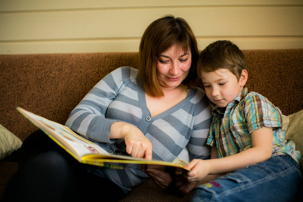 Una mujer le lee un libro a su hijo pequeño, creando un momento de unión y cultivando el amor por las historias. - Foto, imagen