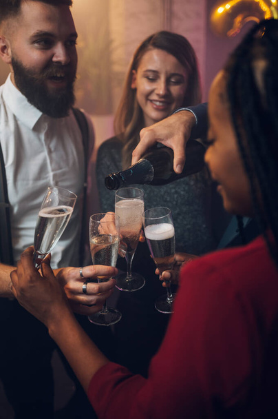 Boldog baráti társaság ünnepli szilveszterkor, miközben pezsgőt isznak egy klubban. - Fotó, kép