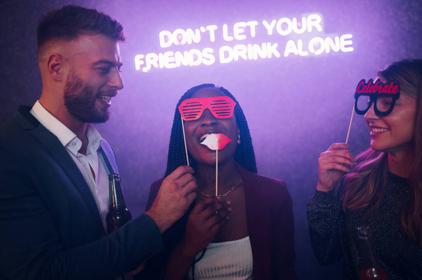Fröhliche Gruppe von Freunden tanzt auf einer Party in einem Club, trinkt und benutzt lustige Gesichtsstützen - Foto, Bild