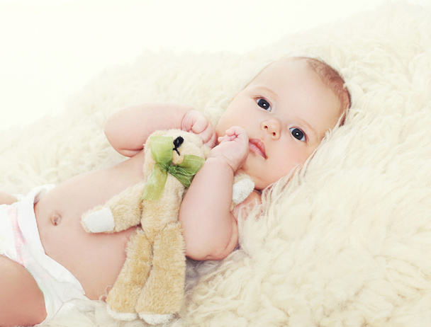 Little baby with teddy bear lying on the bed - Foto, afbeelding