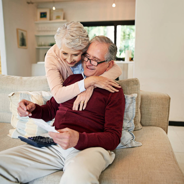 Senior couple, paperwork and hug in home with love, marriage and romance for husband and woman in lounge. Sofa, calculator and maths for bills with document, retirement fund or trust for happy people. - Photo, Image
